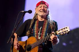 Country music star WIllie Nelson playing his guitar.